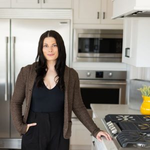 Kyla Franks standing in a Kitchen in a Louis Vuitton sweater.